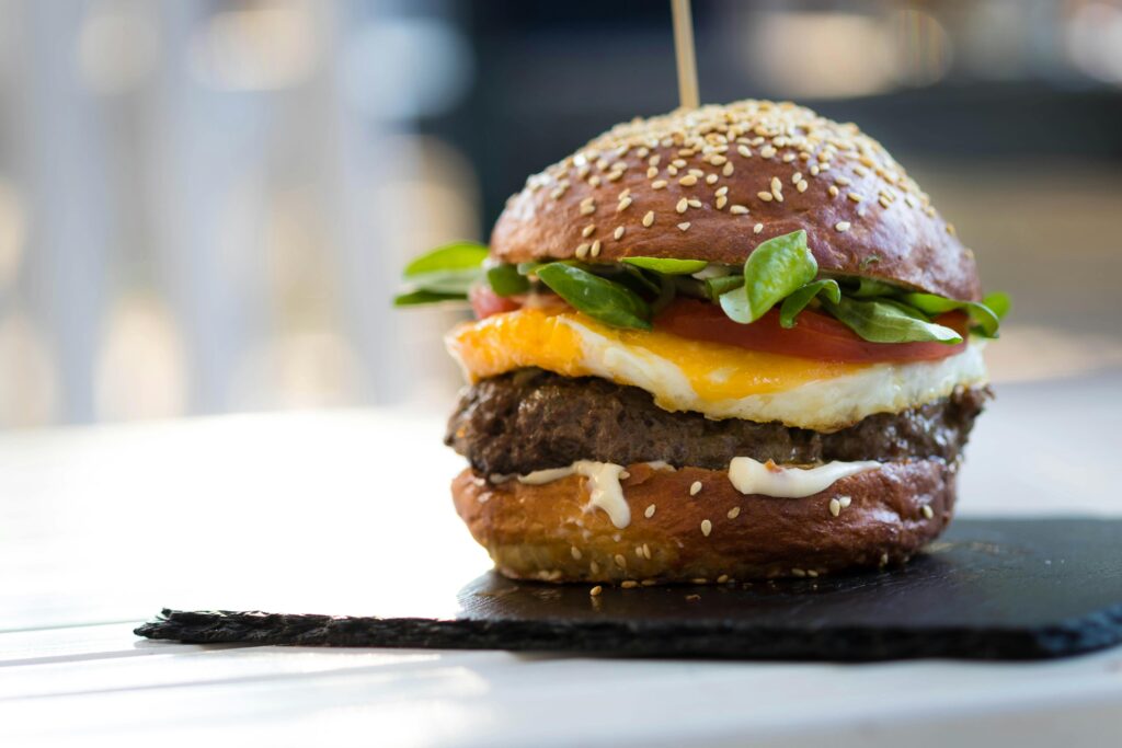 Close-up of a gourmet cheeseburger with spinach and fried egg on a sesame bun.