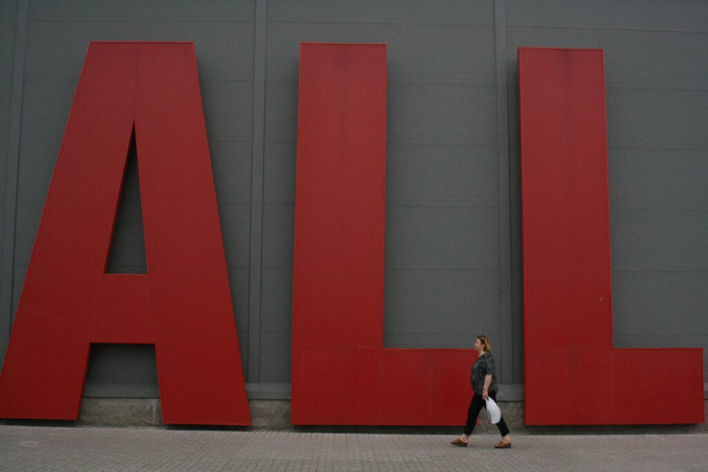 A woman walks past giant red letters spelling 'ALL' in Minsk, Belarus.